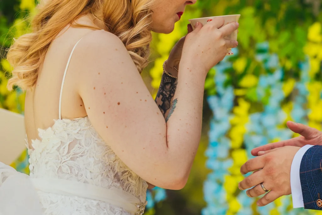 Bride sipping from a teacup among hanging flowers