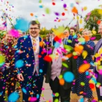 Couple walking through a storm of rainbow confetti