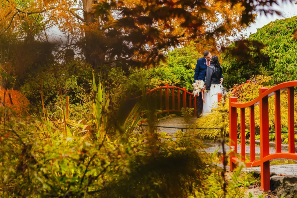 Couple kissing on a red bridge