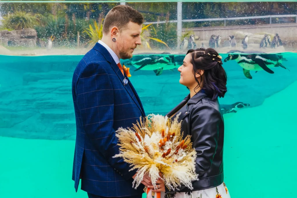 Couple gazing at each other in front of a penguin pool