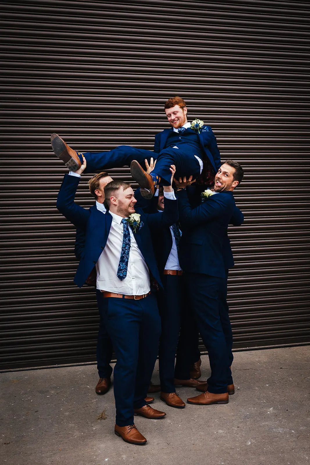 Groom being lifted by his groomsmen