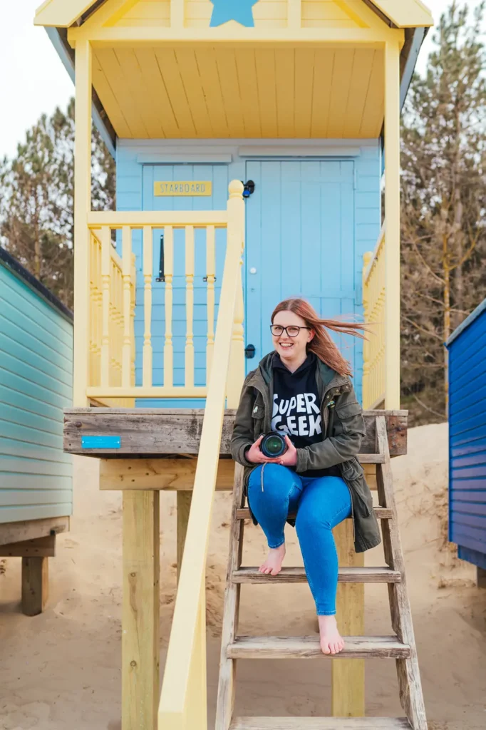 Kirsty sitting on the steps of a blue and yellow beach hut