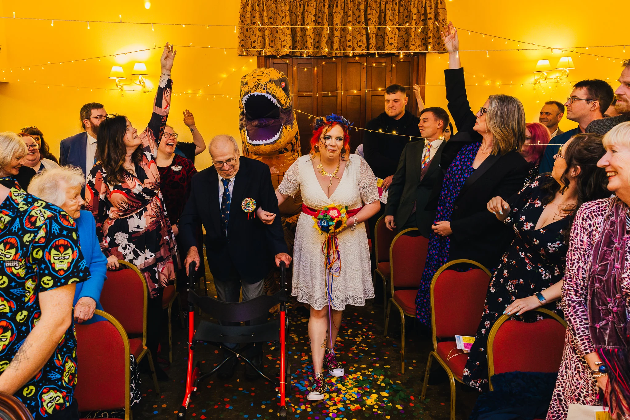 Couple walking back up the aisle as an inflatable dinosaur cheers