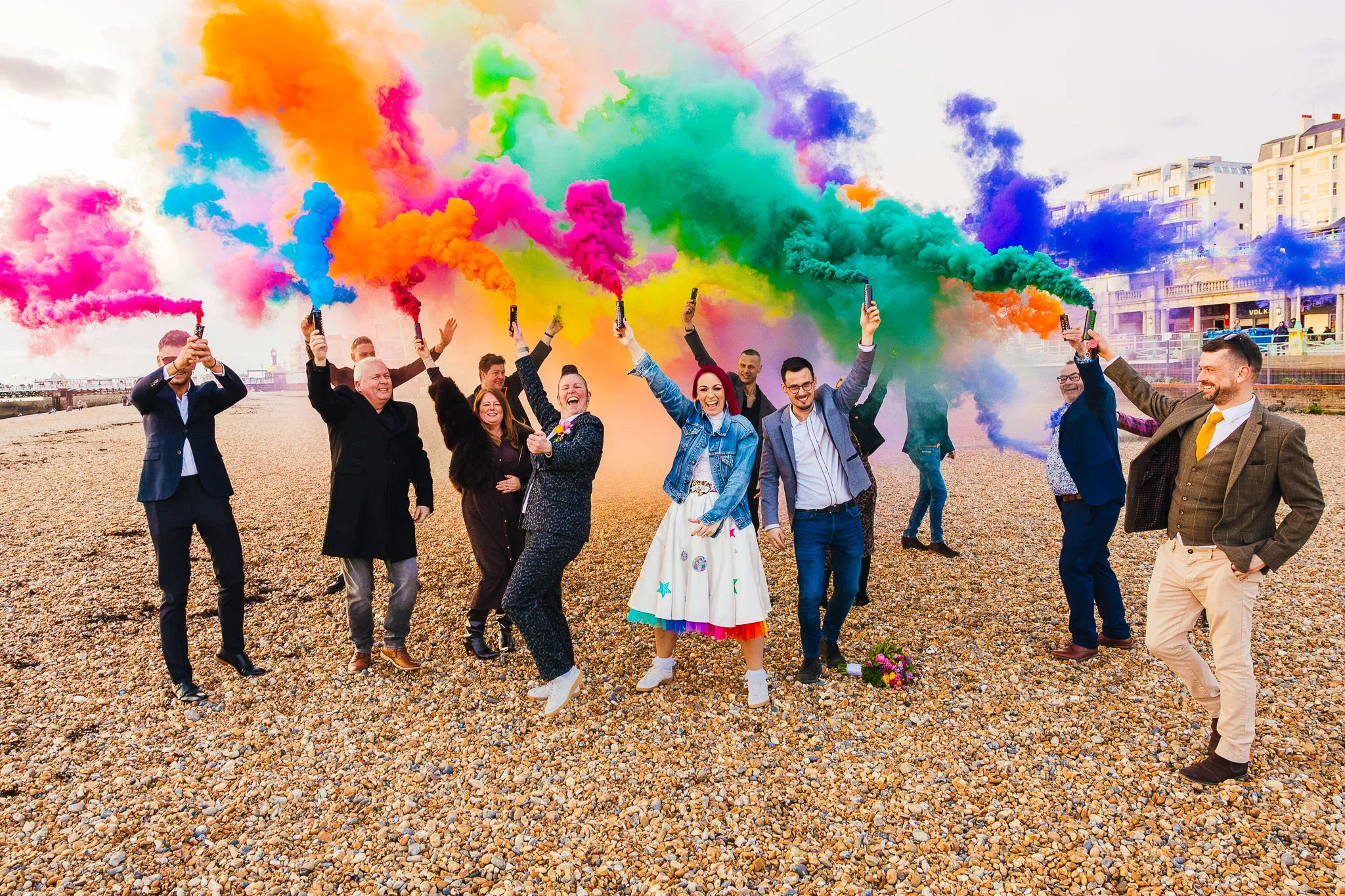 Couple and guests cheering in coloured smoke on Brighton beach