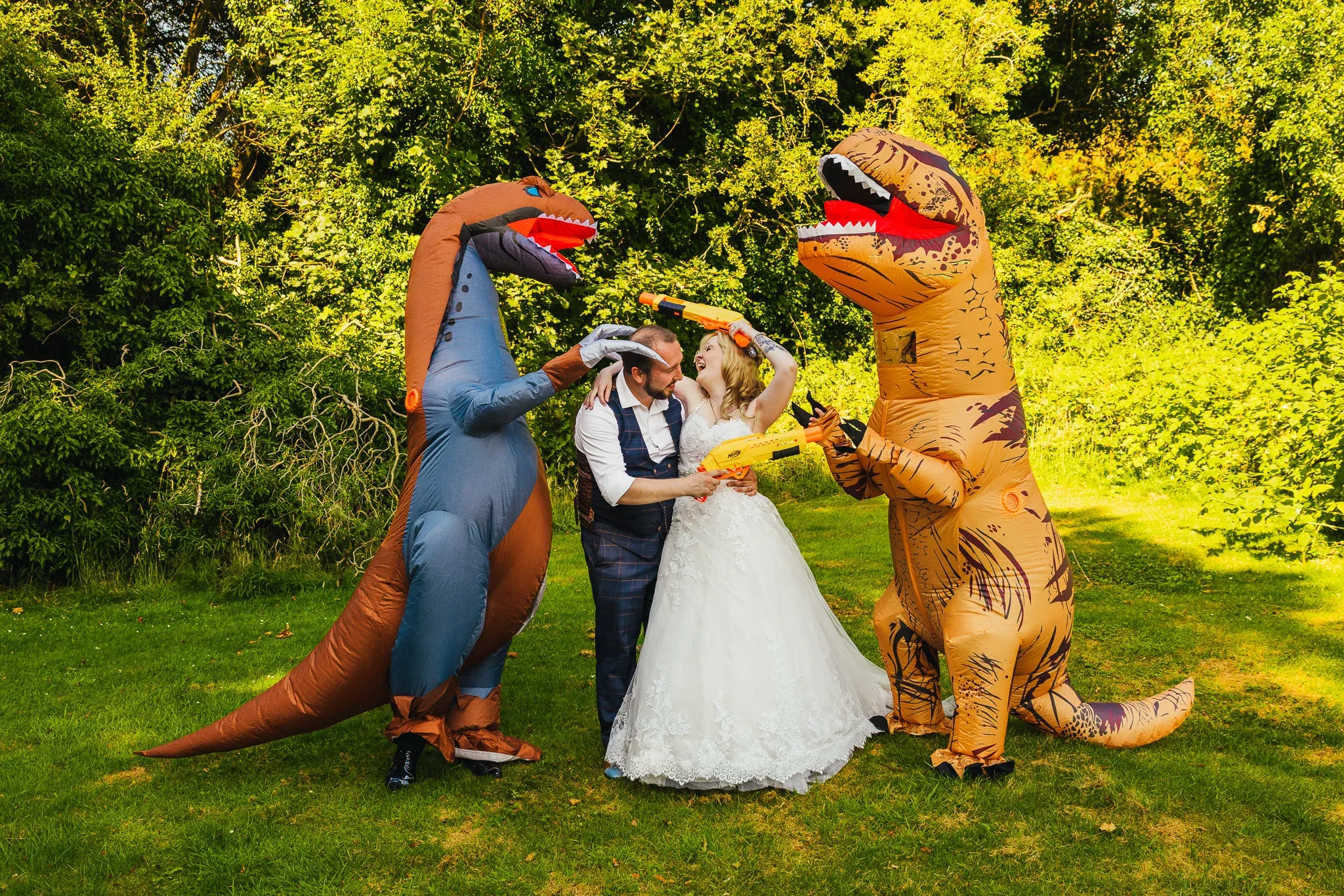 Bride and guests in inflatable T-rex costumes with foam blasters
