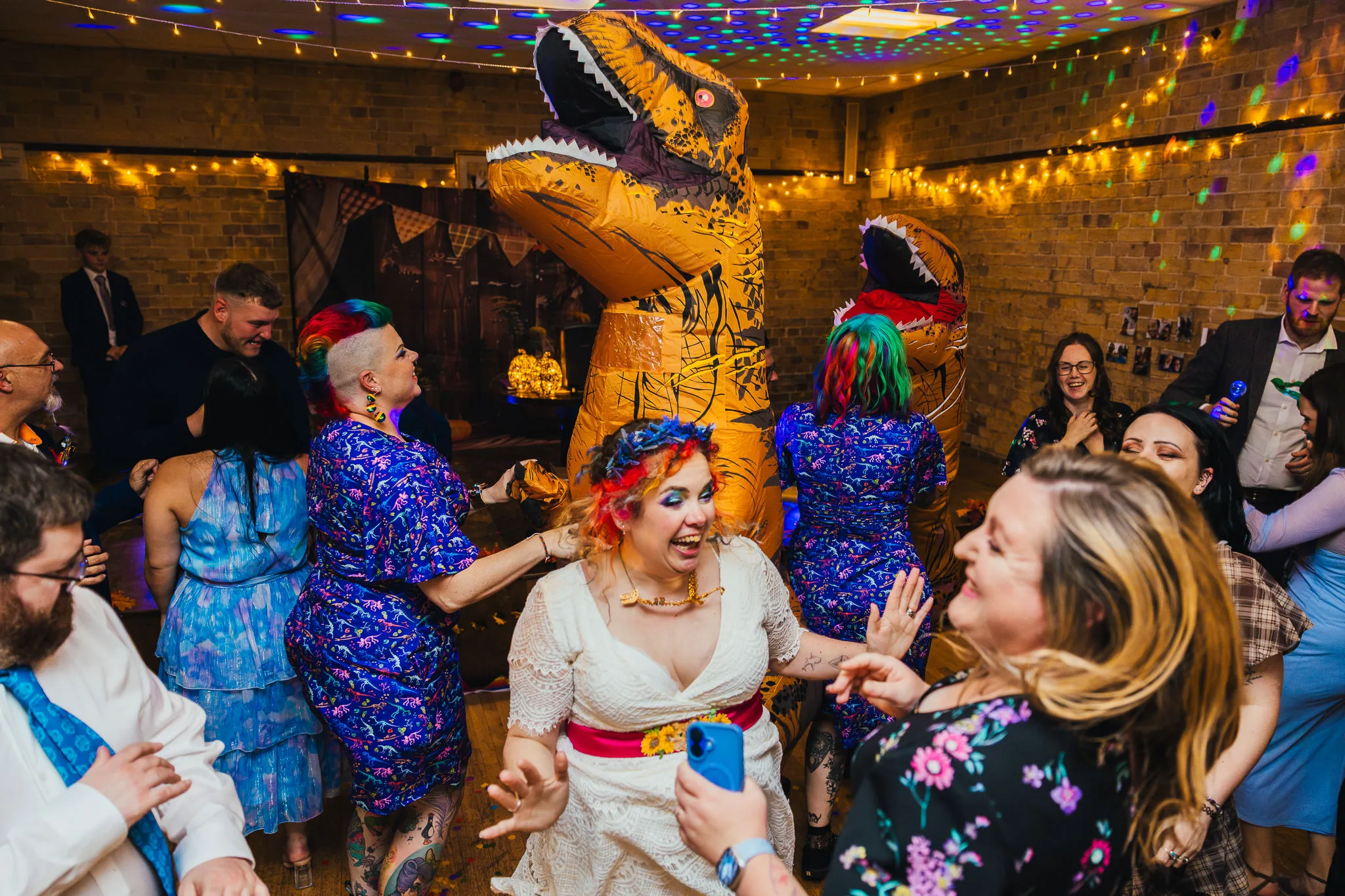 Bride dancing with guests and inflatable dinosaurs