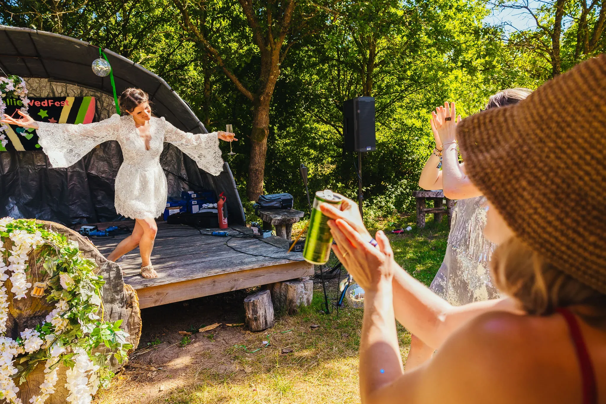 Bride dancing on a stage in the woods at a festival wedding