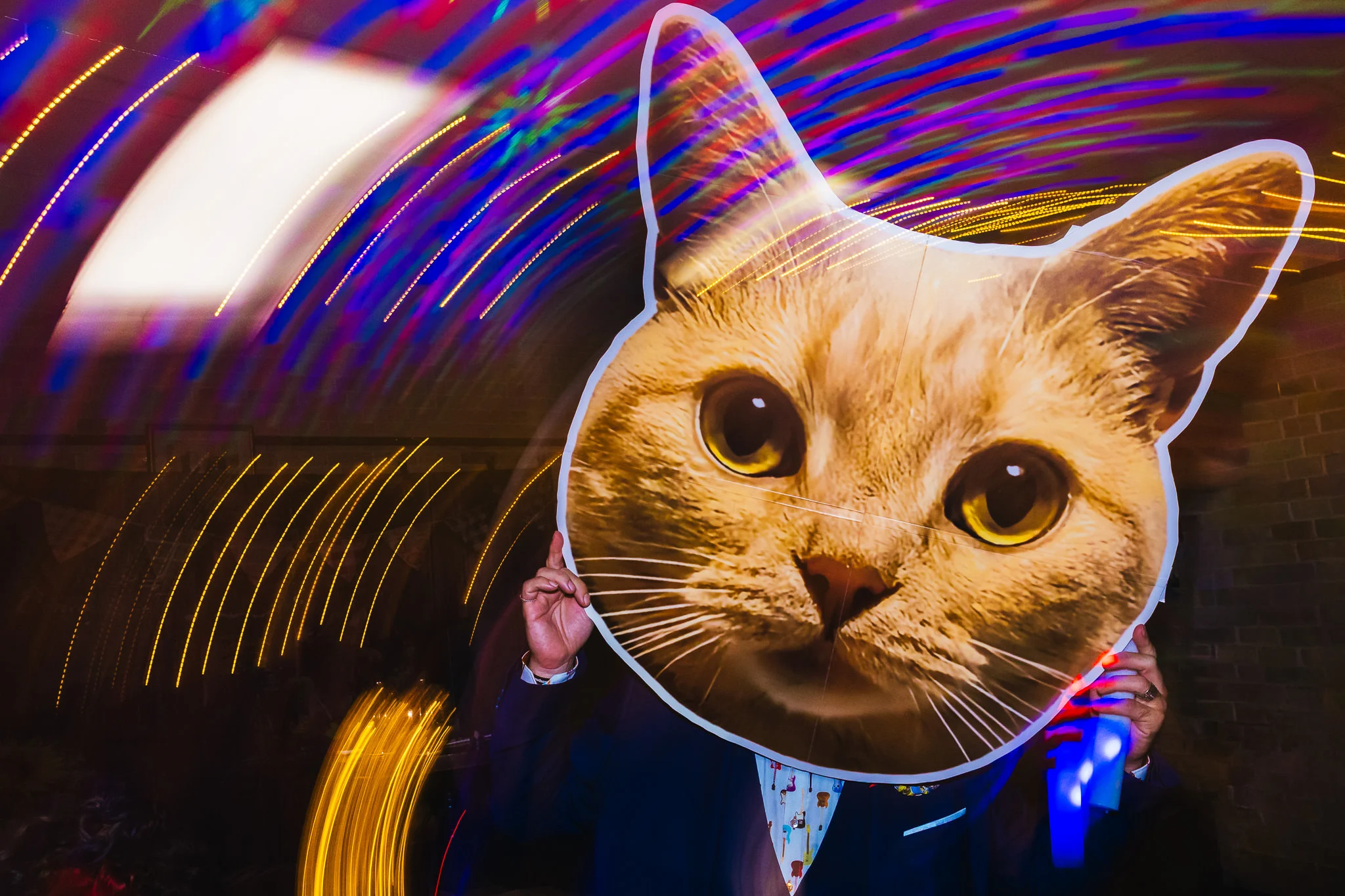 Guest holding up a giant cat face mask on the dance floor