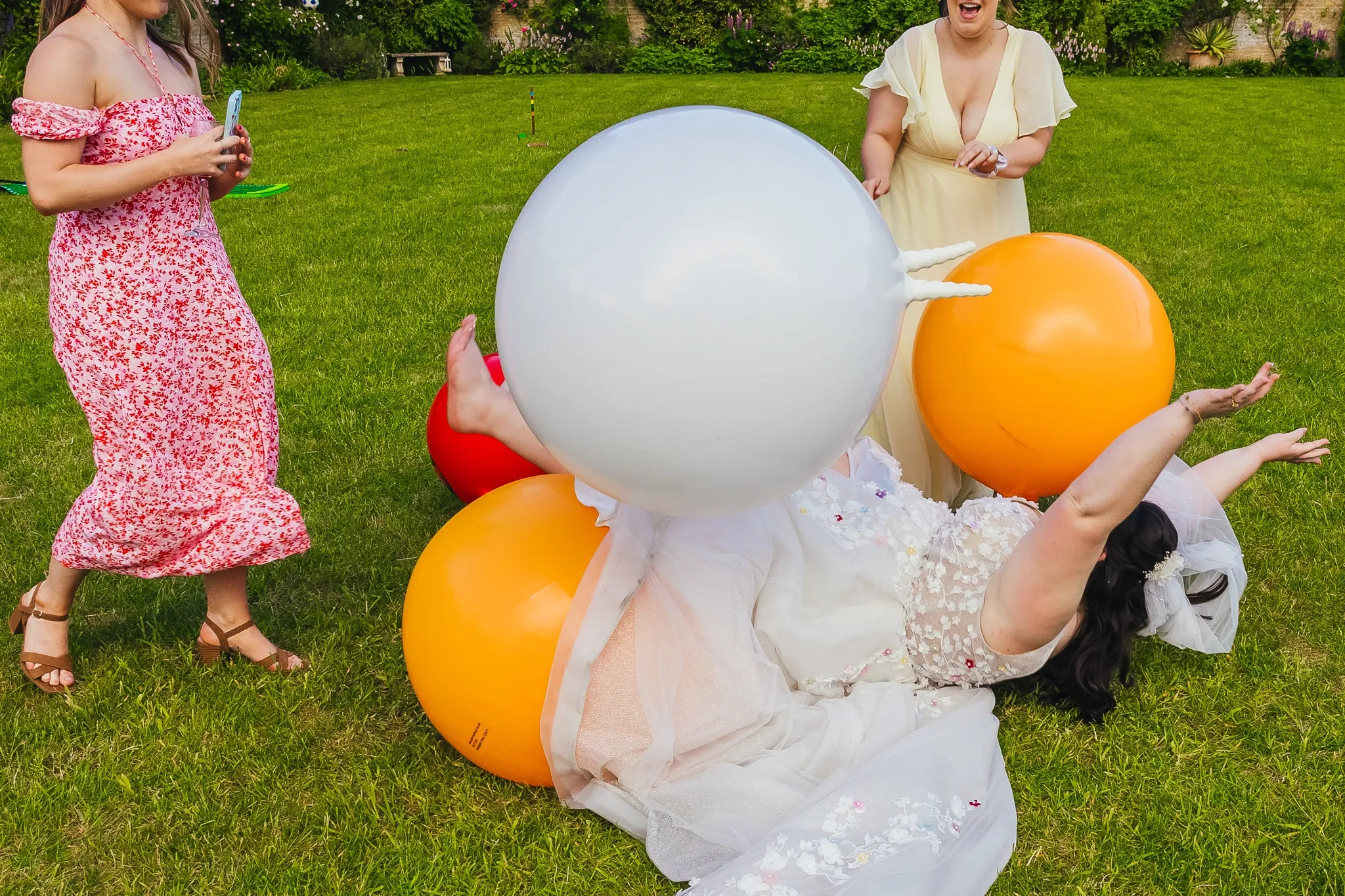 Bride falling over space hoppers in a walled garden