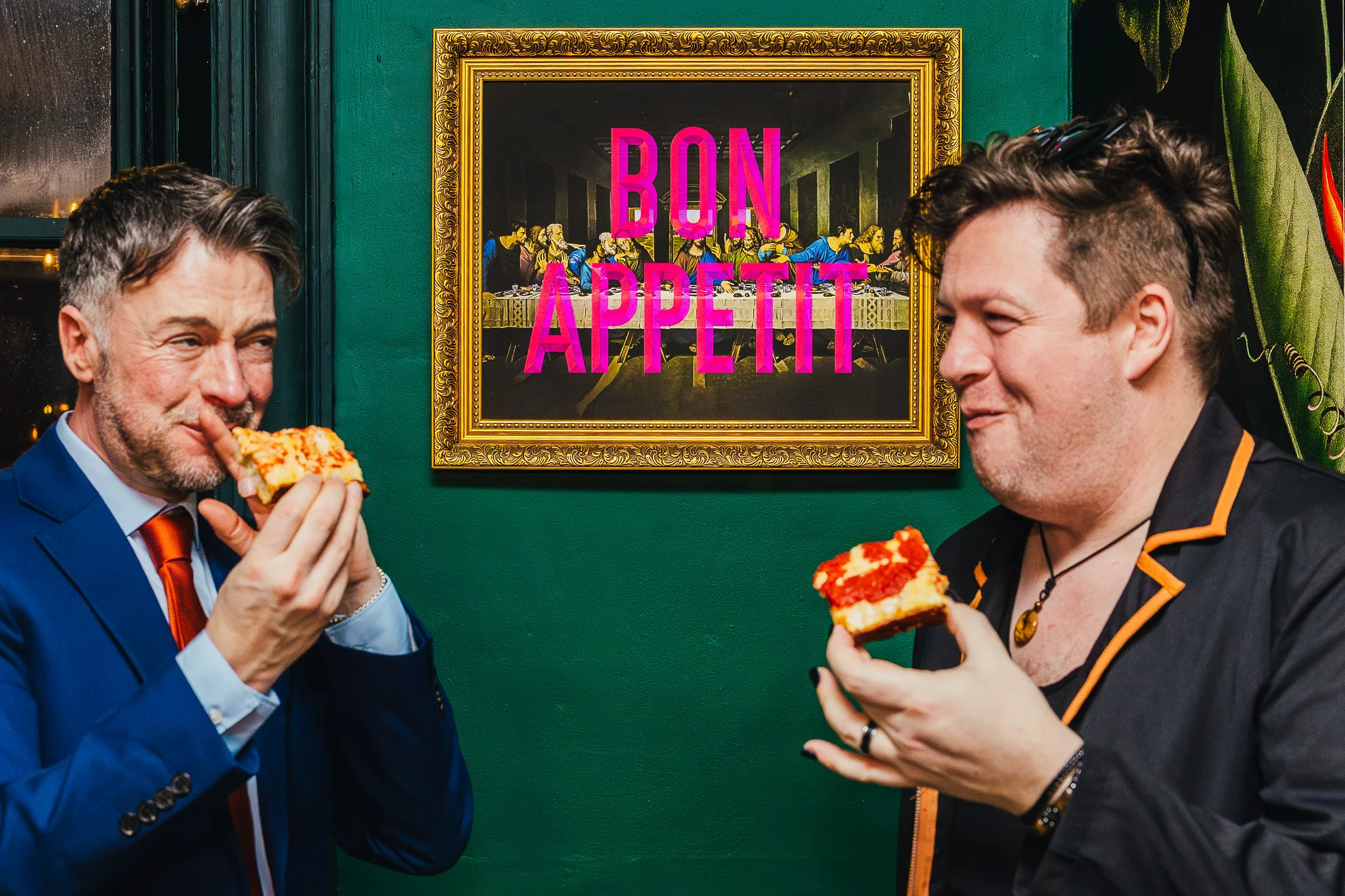 Guest tucking into pizza under a Bon Appetit sign